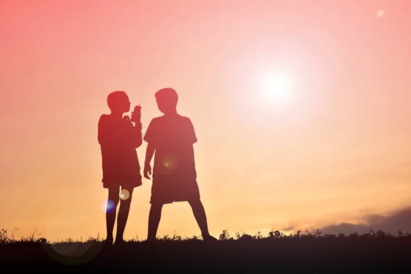 Sziluettjét gyermekek smartphone-on sunset — Stock Fotó