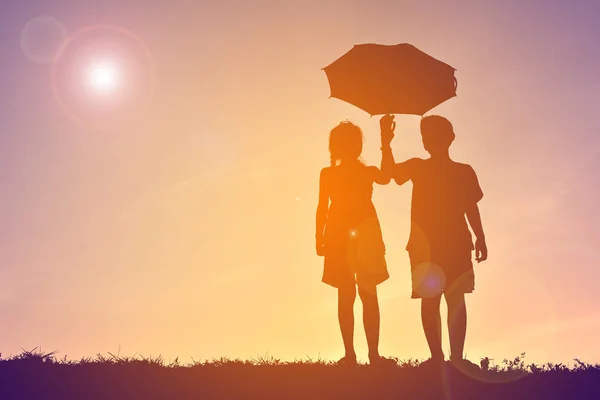 Silhouette enfants avec parapluie au coucher du soleil — Photo