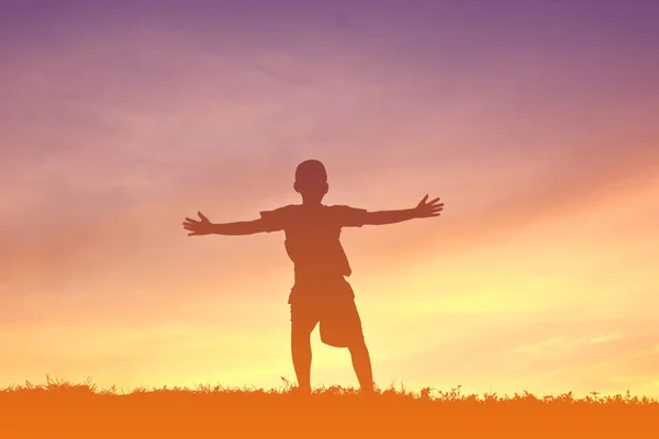 Siluett en pojke koppla av på sunset — Stockfoto