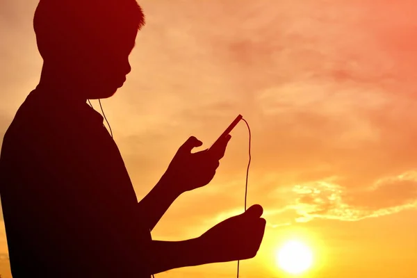 Silhouette garçon avec smartphone au coucher du soleil — Photo