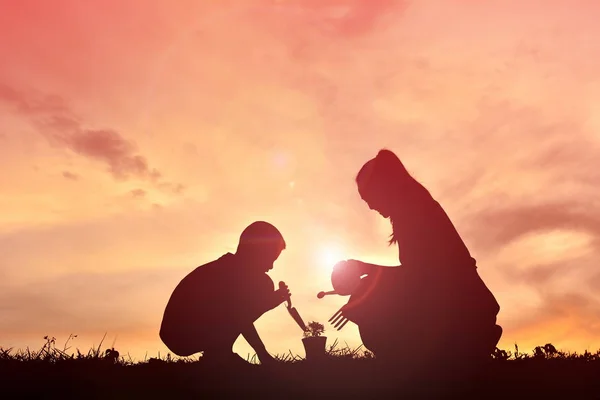 Silhouette mère et fils plantant au coucher du soleil. Concept fête des mères — Photo