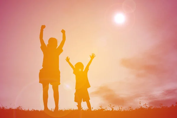 Silhouettes mother and little son playing at sunset — Stock Photo, Image