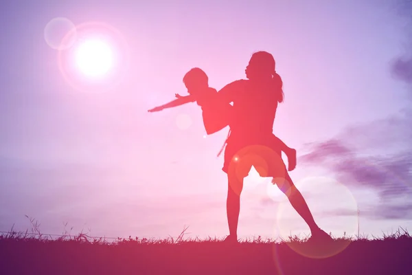 Silhouettes mother and little son playing at sunset — Stock Photo, Image