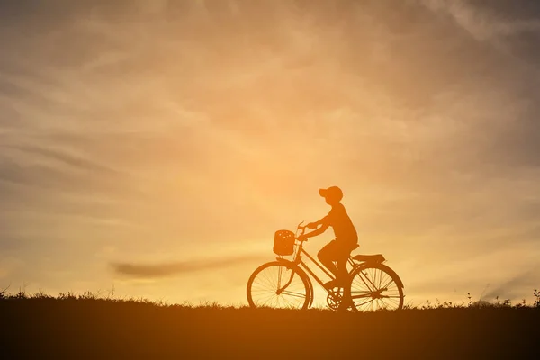 Sylwetka chłopiec z rowerem na zachód słońca — Zdjęcie stockowe