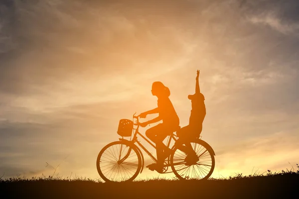Silhueta mulheres e menino com bicicleta no pôr do sol — Fotografia de Stock