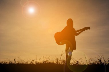 Siluet mutlu kız gökyüzü günbatımı, mutlu zaman gitar çalmak