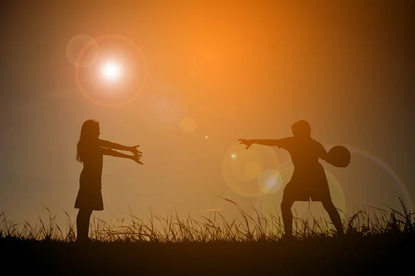 Silueta niños jugando fútbol en el cielo puesta de sol. Tiempo de vacaciones — Foto de Stock