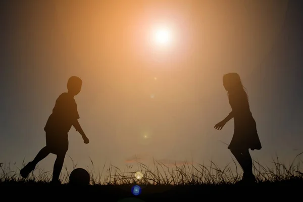 Silhouette enfants jouant au football sur le ciel coucher de soleil. Temps de vacances — Photo