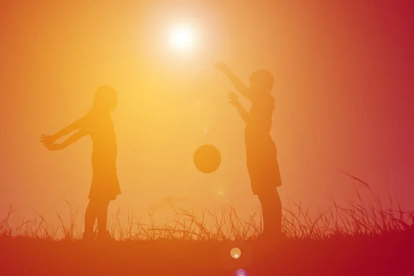 Silhouette enfants jouant au football sur le ciel coucher de soleil. Temps de vacances — Photo