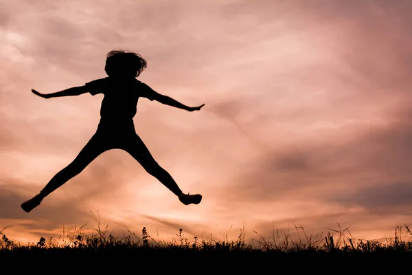 Oynama ve gökyüzü günbatımı atlama mutlu kadın silüeti — Stok fotoğraf