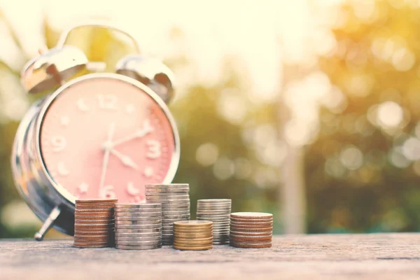 Moneda con despertador en madera vieja y fondo bokeh árbol — Foto de Stock