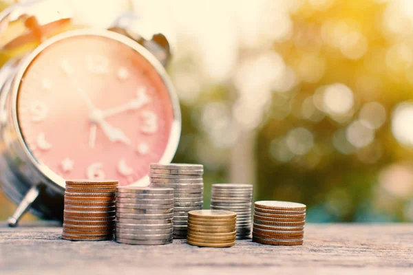 Moneda con despertador en madera vieja y fondo bokeh árbol — Foto de Stock