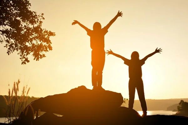 Silhouette of happy women on the rock near the river — Stock Photo, Image