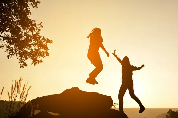 Silhouette glücklicher Frauen auf dem Felsen in der Nähe des Flusses — Stockfoto