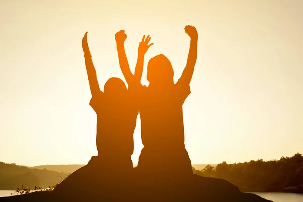 Silhouette glücklicher Frauen auf dem Felsen in der Nähe des Flusses — Stockfoto