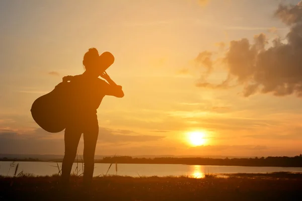 Silhouette de femmes heureuses et guitare au coucher du soleil du ciel — Photo
