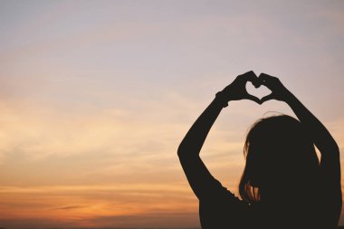 Siluet el gökyüzü günbatımı arka plan, kalp şeklinde kadınların