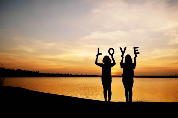 Silueta ženy držící slovo láska na obloze slunce koncept Valentýn — Stock fotografie