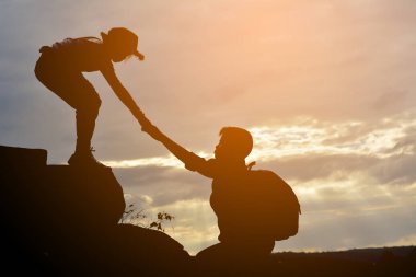 Silhouette of girl helps a boy on mountain  clipart