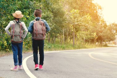 Mutlu Asya çocuk yol ve orman arka planda sırt çantası