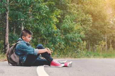 Mutlu Asya çocuk yol ve orman arka planda sırt çantası