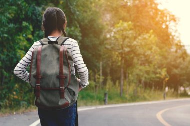 Yol ve orman arka planda mutlu Asyalı kız sırt çantası