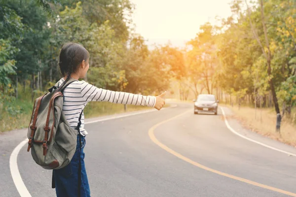 Happy Asian girl backpack in the road and forest background — Stock Photo, Image