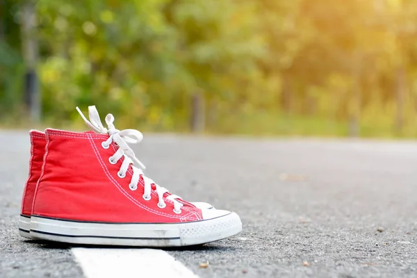 Zapatillas rojas en el fondo de la carretera .hipster tono — Foto de Stock