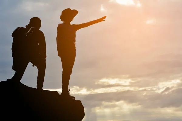 Silhouette di ragazza e ragazzo sulla roccia al tramonto del cielo — Foto Stock