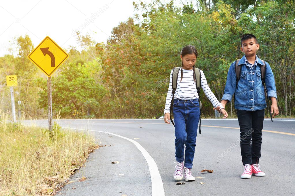 Happy Asian children backpack in the road and forest background