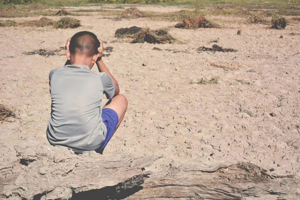 Triste un niño sentado en tierra seca .concept esperanza y sequía — Foto de Stock