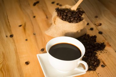 Sıcak kahve fincanı ve fasulye çanta vintage ahşap arka plan sesi olarak