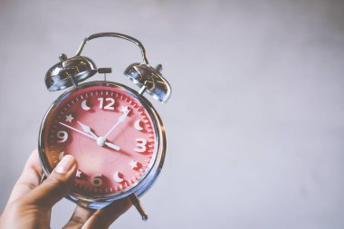 Yakın çekim el çalar saat gri arka plan üzerinde tutarak