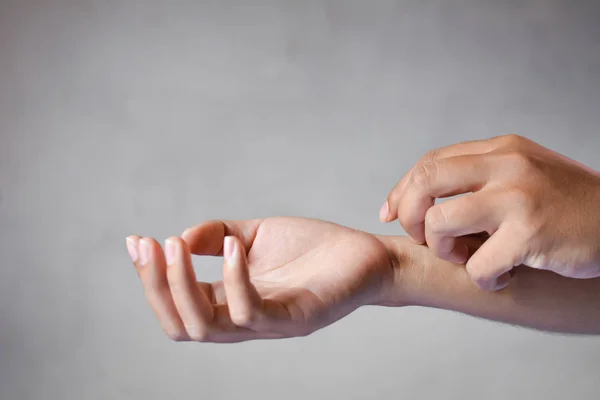 Close up of people scratch  itch hand  on gray background — Stock Photo, Image