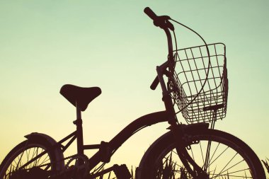 Gökyüzü günbatımı ile çimenlerin üzerinde bisiklet silüeti