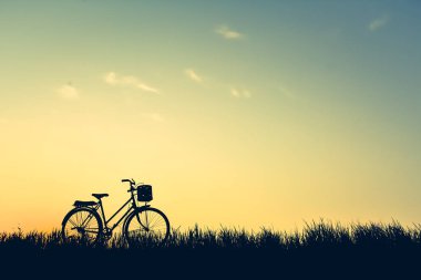 Eski gökyüzü günbatımı, rengini çim üzerinde bisiklet siluet