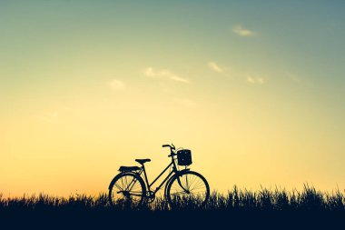 Eski gökyüzü günbatımı, rengini çim üzerinde bisiklet siluet