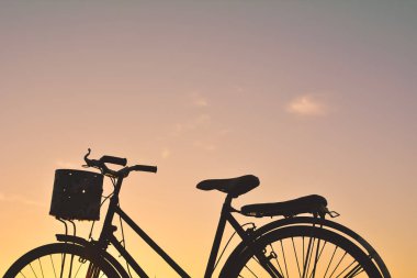 Eski gökyüzü günbatımı ile çimenlerin üzerinde bisiklet siluet