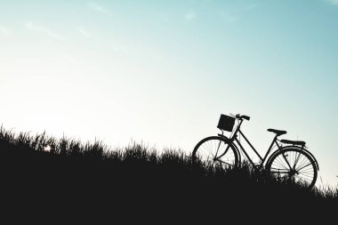 Eski gökyüzü günbatımı ile çimenlerin üzerinde bisiklet siluet
