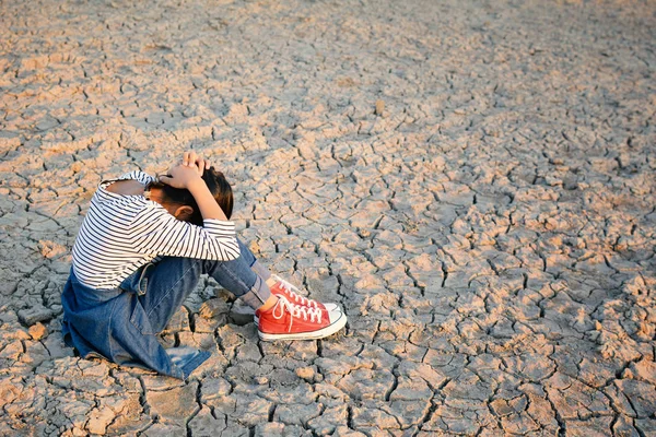 Triste una chica sentada en tierra seca .concept esperanza y sequía — Foto de Stock