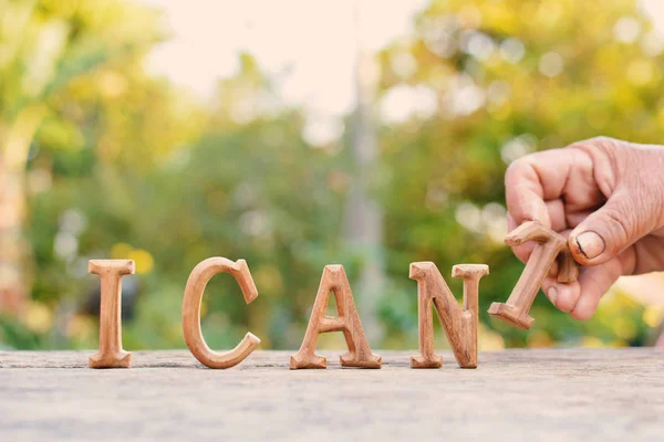 Handen håller alfabetet trä "Jag kan" ordet på trädet bokeh bakgrund — Stockfoto