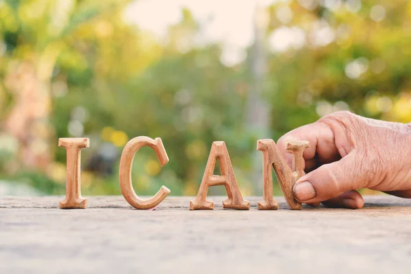 Handen håller alfabetet trä "Jag kan" ordet på trädet bokeh bakgrund — Stockfoto