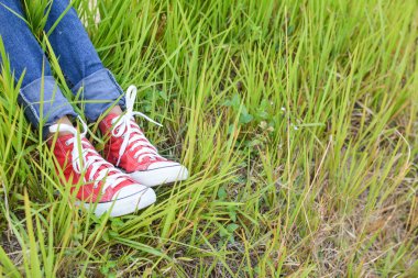 Ayakları kırmızı spor ayakkabı bir kız doğada ve tatil zamanında rahatla. sel