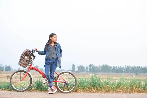 Menina feliz com bicicleta no campo de grama, foco seletivo e macio — Fotografia de Stock