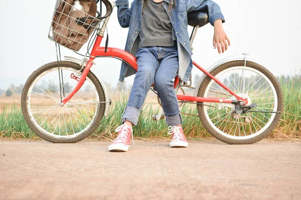 Щаслива дівчина з велосипедом на трав'яному полі, вибірковий і м'який фокус — стокове фото