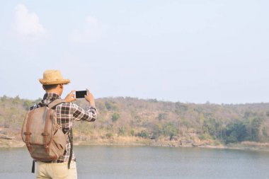 Doğa arka planda mutlu Asya hipster adam sırt çantası