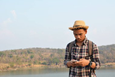 Doğa arka planda mutlu Asya hipster adam sırt çantası