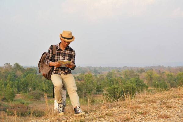 Счастливый азиатский хипстер в рюкзаке на фоне природы

