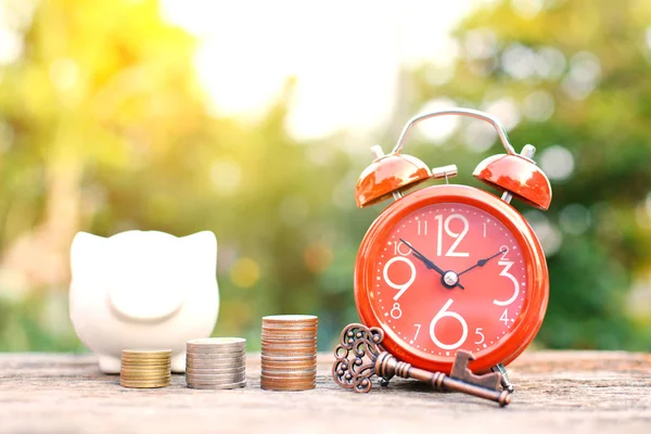 Reloj despertador rojo con moneda en madera vieja — Foto de Stock