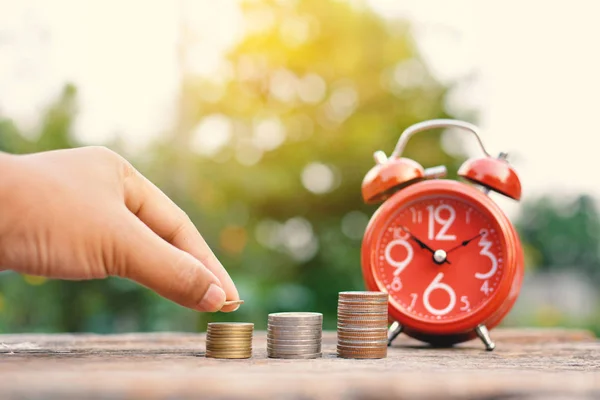 Moneda de mano con despertador rojo en madera vieja — Foto de Stock